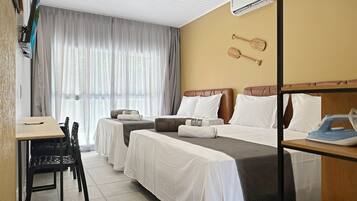 A hotel room with two beds, a desk, a chair, and a dining table.