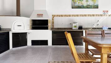 A kitchen with a built-in oven, a painting of palm trees, and a tiled backsplash.