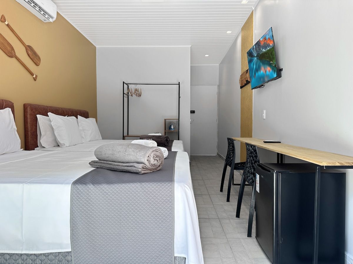 Une chambre d’hôtel équipée d’un lit, d’un bureau, d’une chaise, d’une télévision et d’un appareil de climatisation.