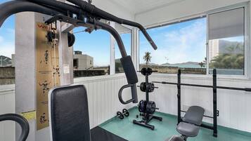 A gym with exercise equipment, a bench, and a view of the city.