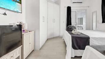 A hotel room with a bed, a TV, a wardrobe, and a bathroom with a mirror and sink.