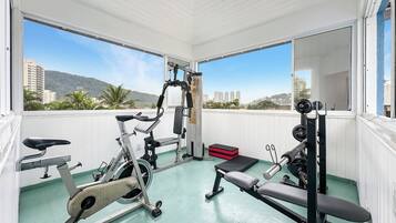 A gym with exercise equipment, large windows, and a view of buildings and hills.