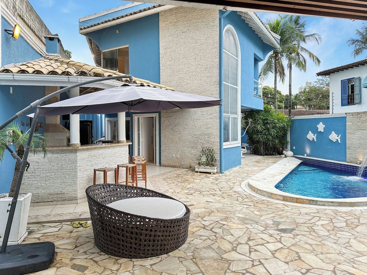 A poolside area with a stone floor, outdoor seating, and a pool with a blue border.