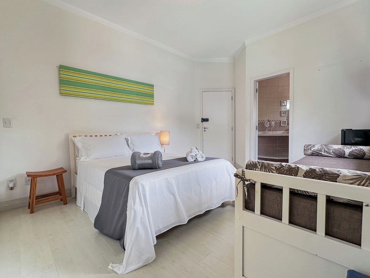 A bedroom with a bed, a bedside table, a lamp, and a view through a window.