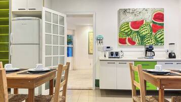 A modern kitchen with a dining area, white cabinets, a microwave, and a painting of watermelons on the wall.