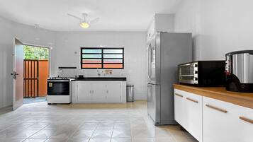 A modern kitchen with white cabinets, a stainless steel refrigerator, a built-in oven, and a microwave.