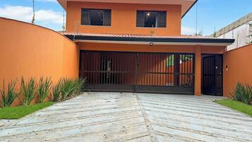 A modern house with a flat roof, a paved driveway, and a gated entrance.