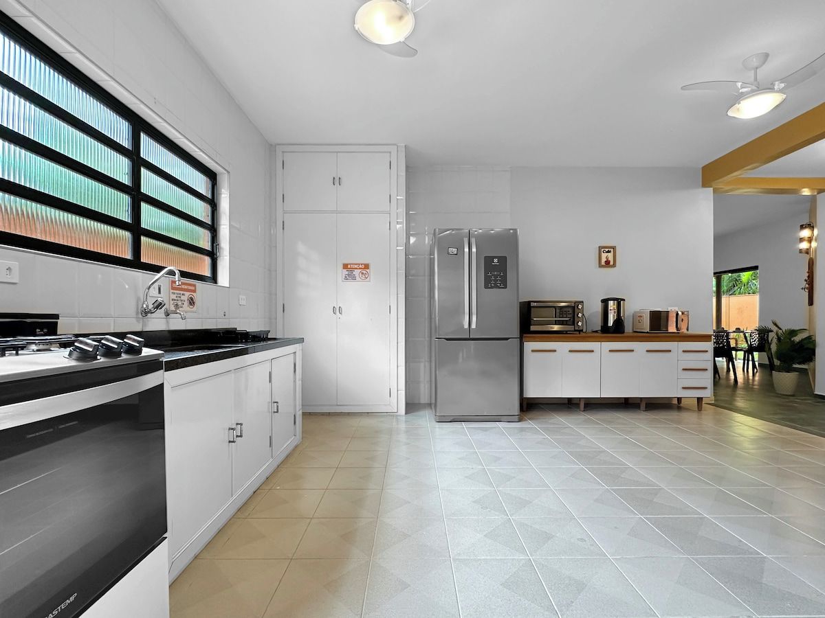A modern kitchen with stainless steel appliances, white cabinetry, and a tiled floor.