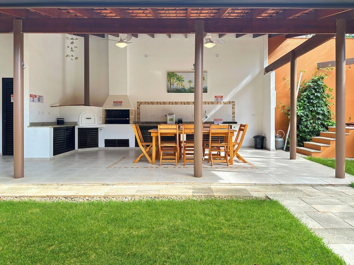 Un área de cocina exterior con una parrilla, una mesa de comedor y sillas.