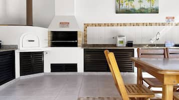 A kitchen with a built-in oven, a painting of palm trees, and a tiled backsplash.