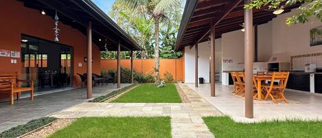 A covered outdoor area with a patio, seating, and a palm tree.