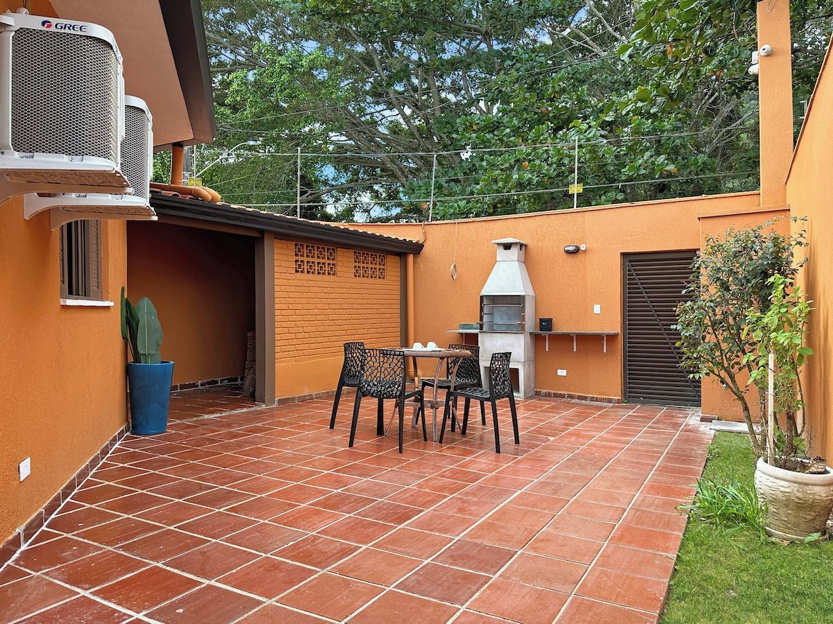 An outdoor patio with a barbecue grill, a table with chairs, and a potted plant.