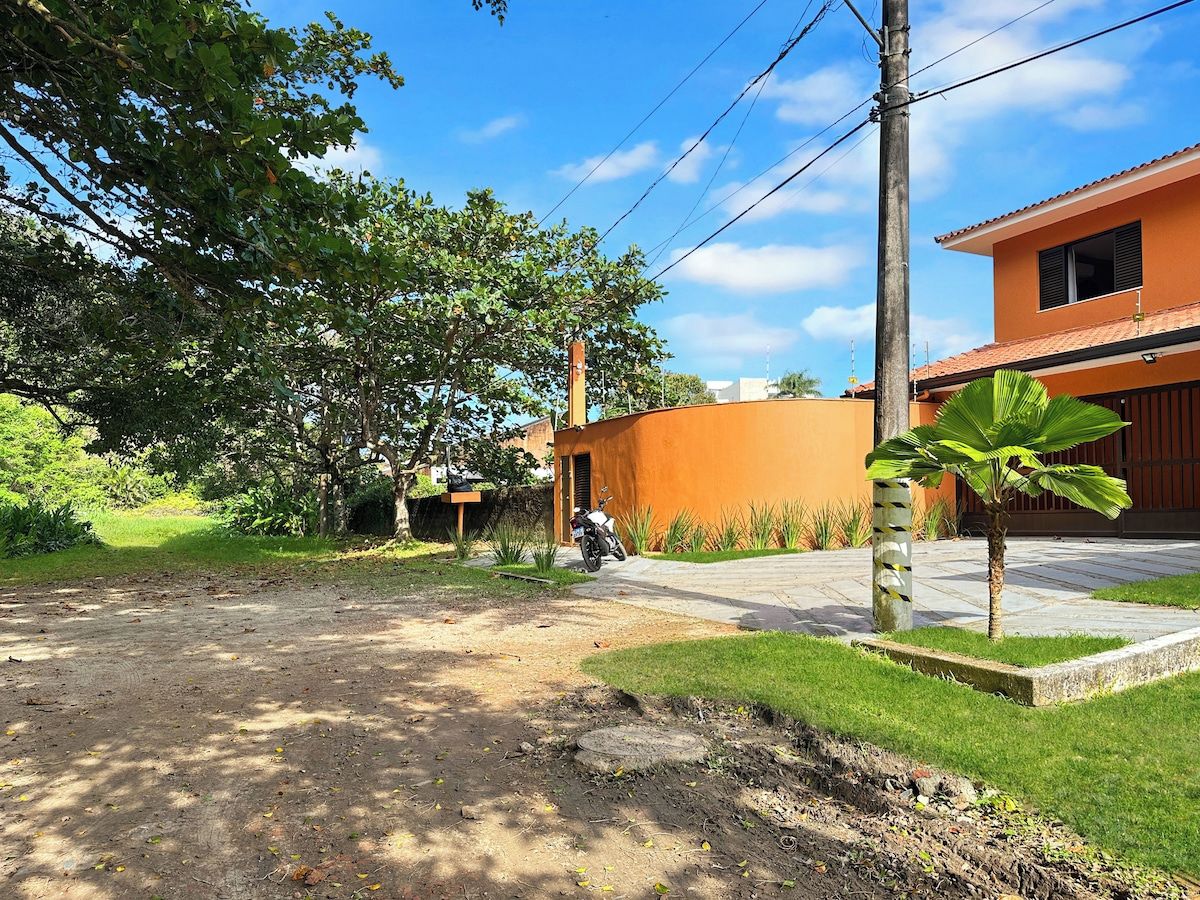 Un barrio residencial con un camino pavimentado, una motocicleta estacionada y una palmera pequeña.