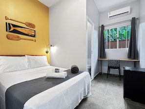 Une chambre d’hôtel avec un lit, un bureau, une chaise et une fenêtre avec des rideaux.