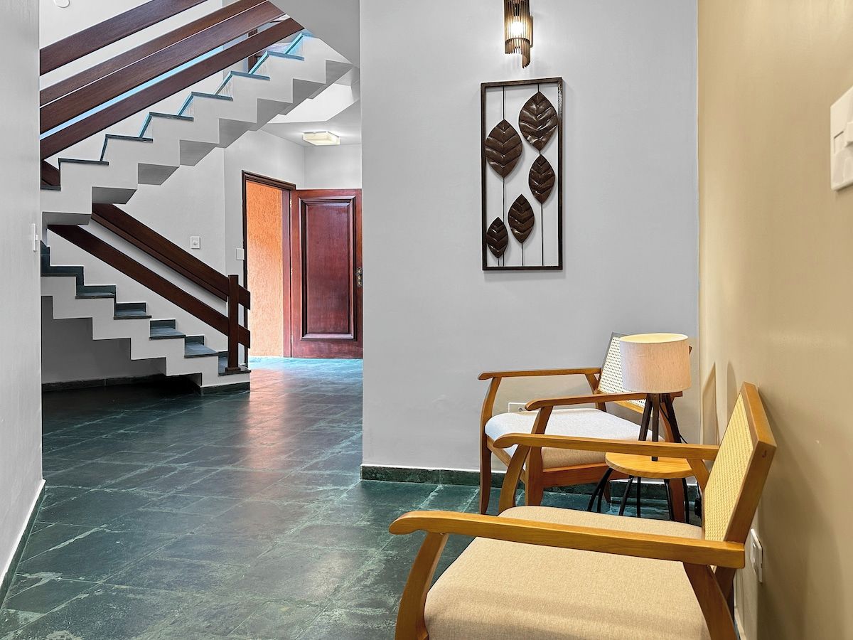 A hallway with a staircase, a wooden bench, a wall-mounted light fixture, and a door.