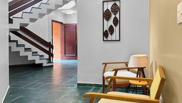A hallway with a staircase, a wooden bench, a wall-mounted light fixture, and a door.