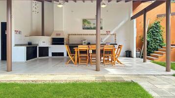 An outdoor kitchen area with a grill, dining table, and chairs.