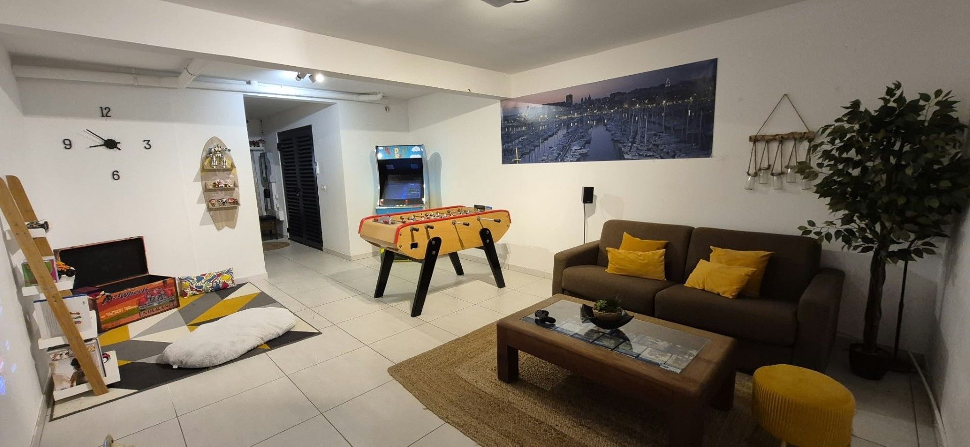 A living room with a sofa, coffee table, and a gaming table.