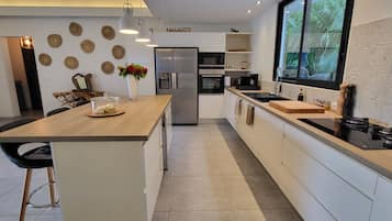 A modern kitchen with a central island, built-in appliances, and a view of the outdoors.