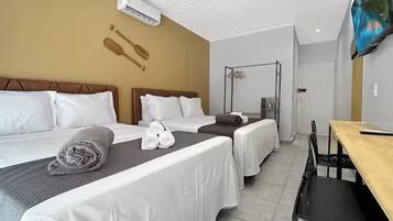 A hotel room with two beds, a wooden headboard, a TV, and a small table.