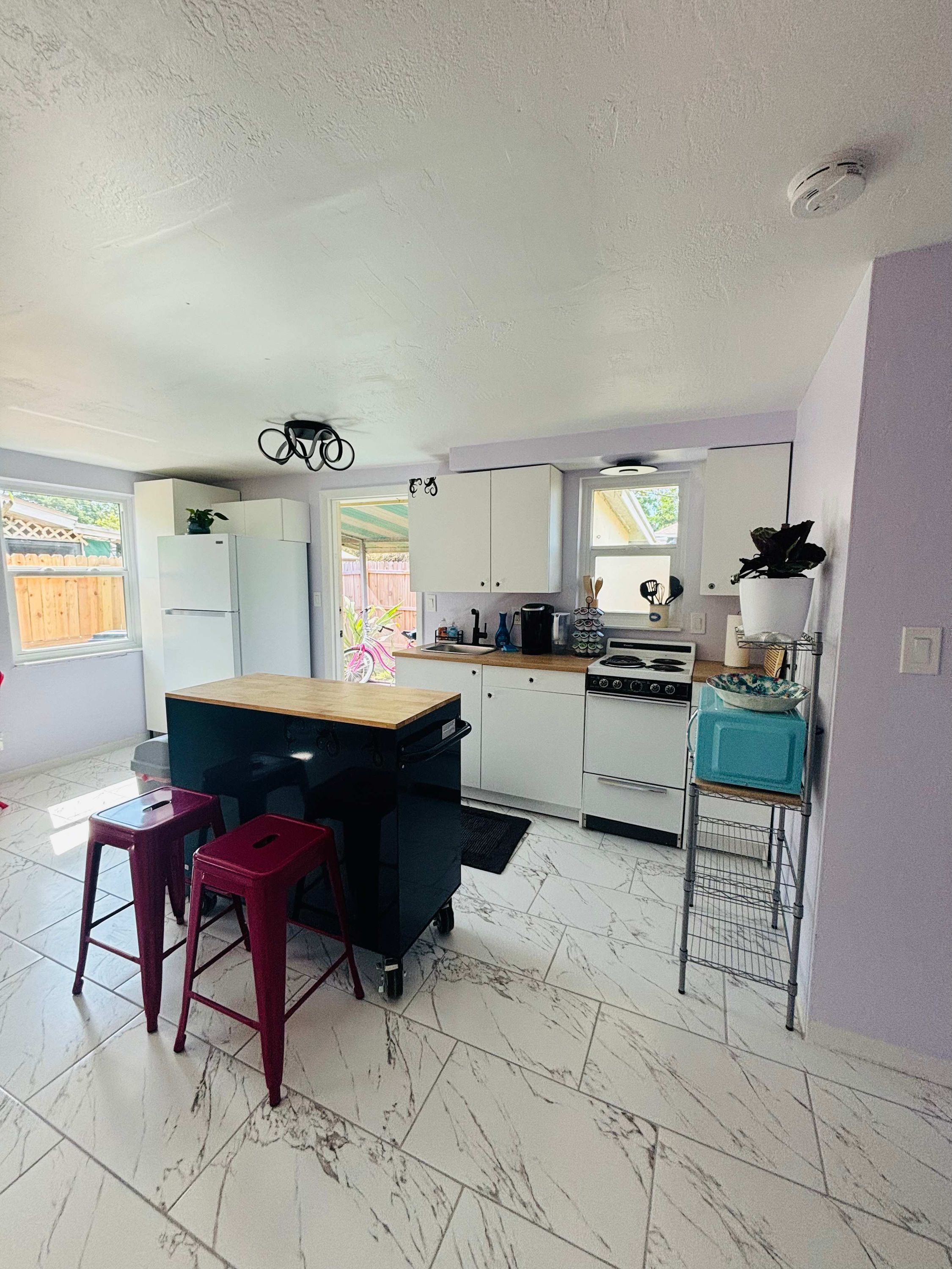 Una cocina compacta con refrigerador, estufa y un pequeño comedor con taburetes.