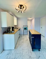 Una cocina moderna con armarios blancos, encimera de madera, horno empotrado y un microondas en un estante.