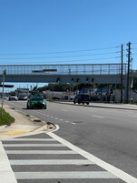 Una carretera con varios carriles, un paso de peatones y un semáforo colgante.