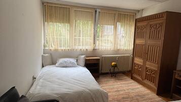 Un dormitorio con dos camas, un radiador, un armario de madera y una silla.