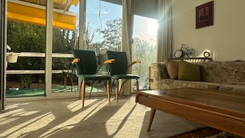A living room with a sofa, chairs, a coffee table, and a view through large windows.