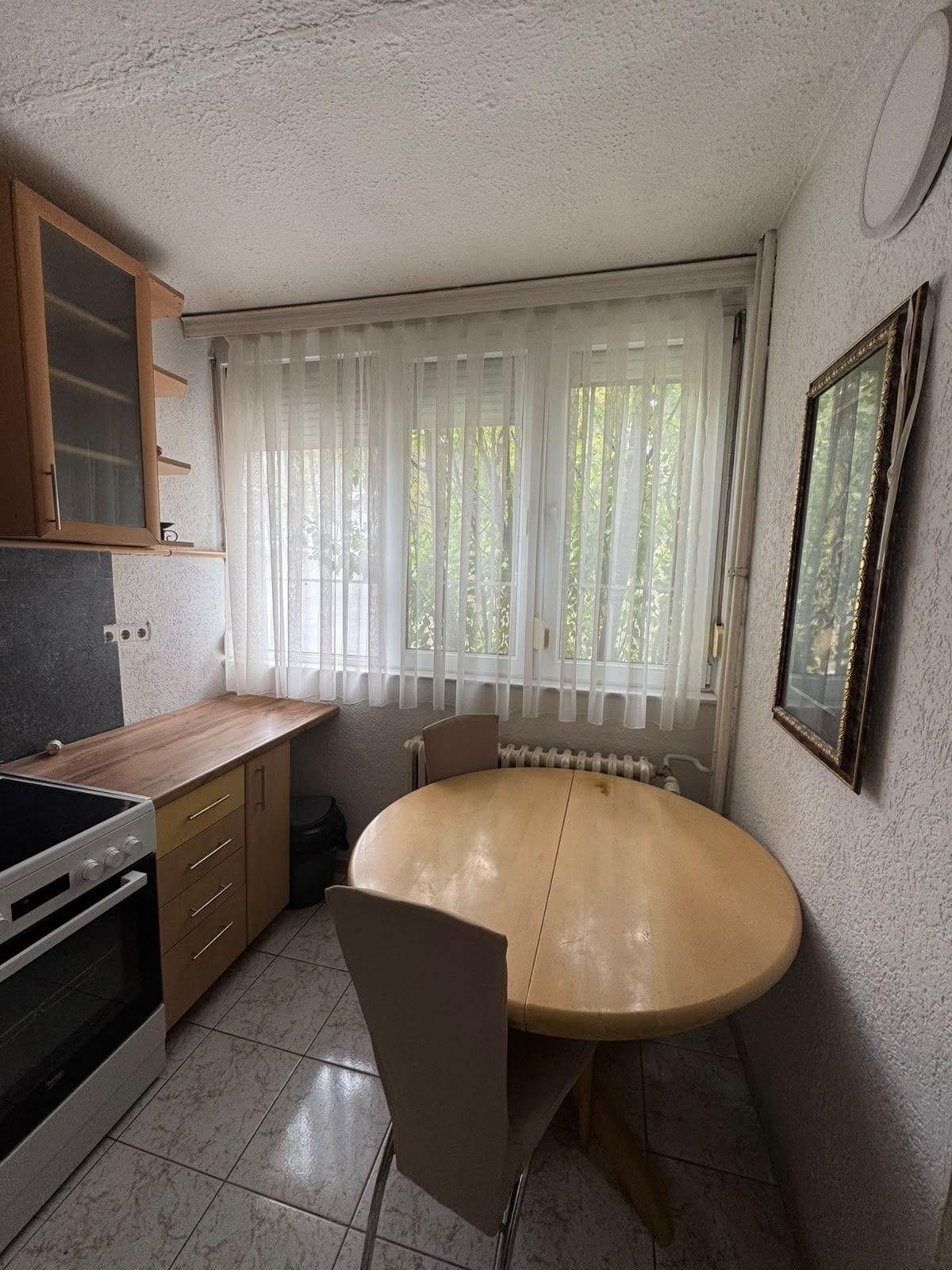 Una cocina funcional con estufa, armarios y una mesa de comedor con sillas.