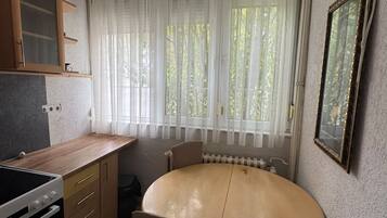 Una cocina funcional con estufa, armarios y una mesa de comedor con sillas.