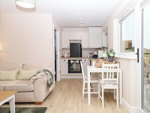 A compact living space with a kitchenette, a dining area, and a sofa. - Little Folley (Exeter)