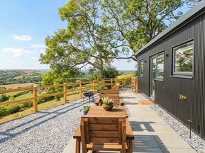 A wooden deck with a table and chairs, overlooking a rural landscape. - Little Folley (Exeter)