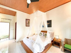 Un dormitorio con cama a dosel, una mesita de noche con lámpara y un banco verde.