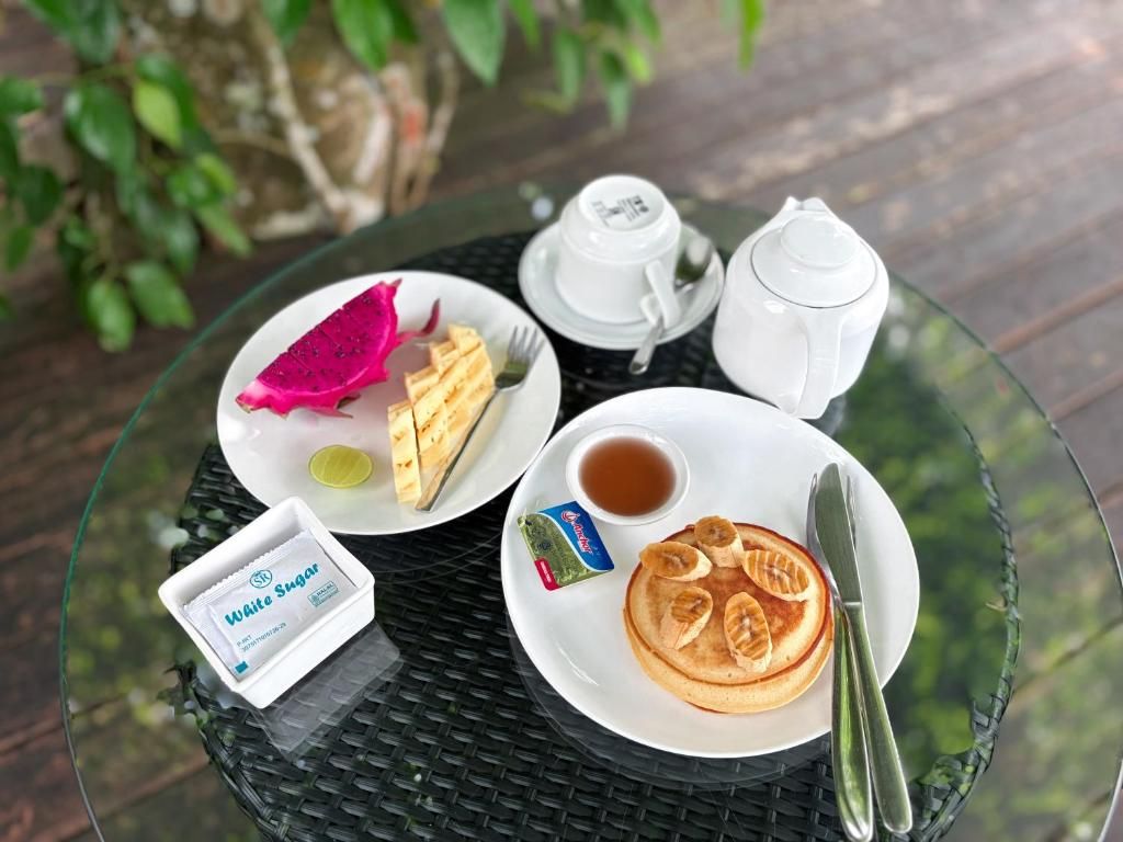 Ein Tisch mit Pfannkuchen, einer Teekanne, einer Tasse, einer kleinen Zuckerdose und einer Butterpackung.