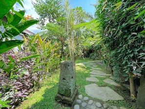 A garden with a stone pathway, lush greenery, and a variety of plants.