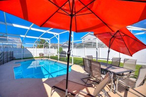 A backyard with a swimming pool, outdoor furniture, and a covered patio area. - Disney Pool Escape | Game Room + Sleeps 14 (Davenport)