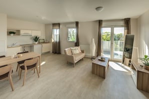 A modern apartment with a dining area, a sofa, a balcony, and a kitchen. - Zenao Appart'hôtels Bègles (Bègles)