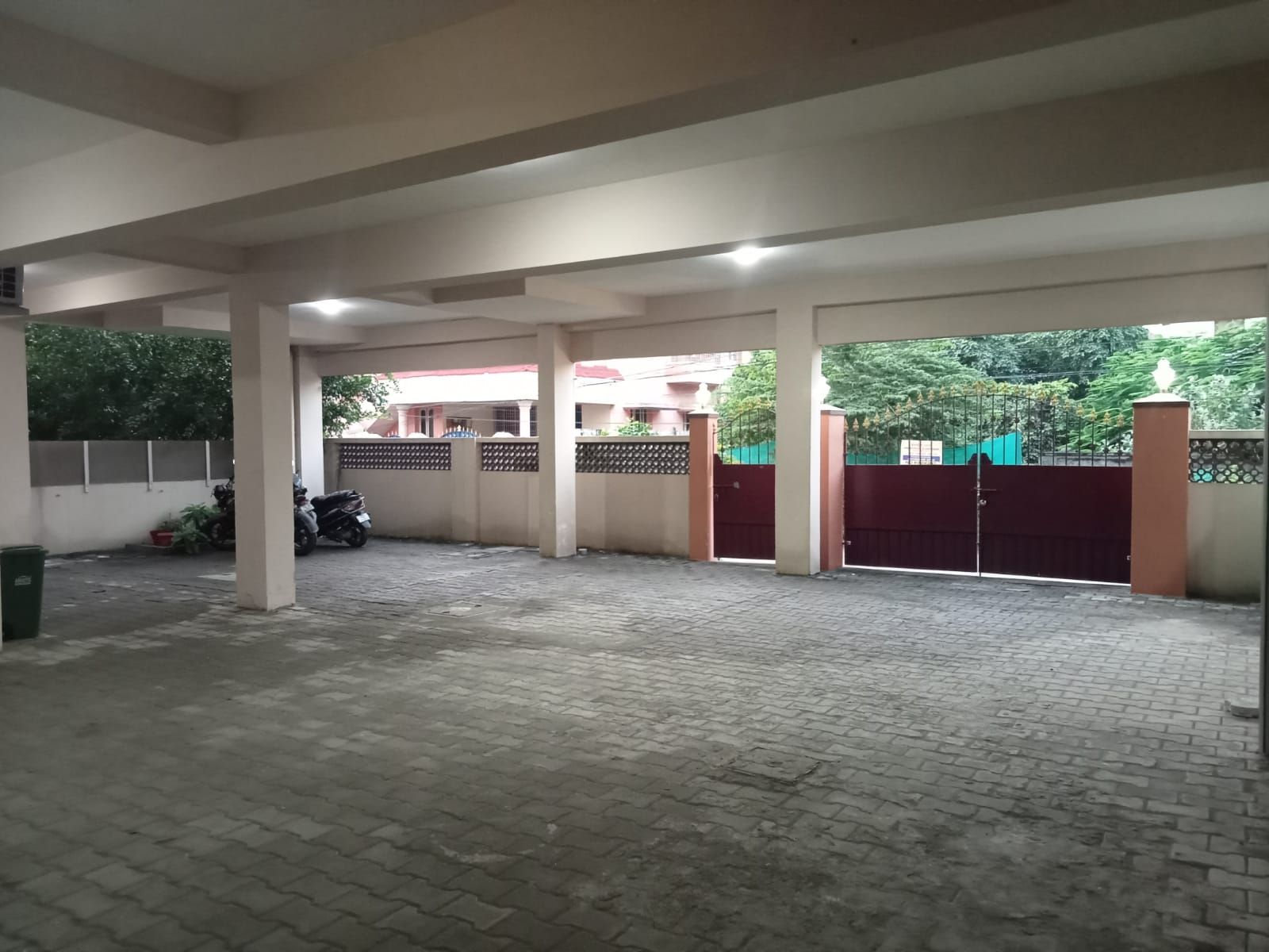 A covered parking area with a paved floor, a motorcycle, and a gated entrance.