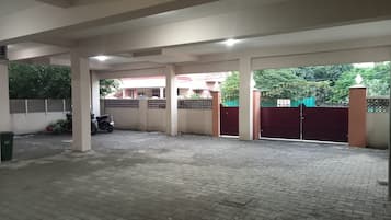 A covered parking area with a paved floor, a motorcycle, and a gated entrance.