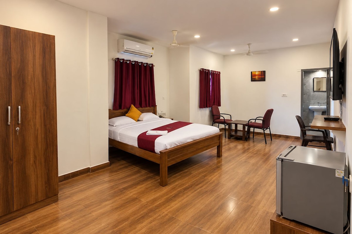 Una habitación de hotel con cama, escritorio, silla, refrigerador y armario.