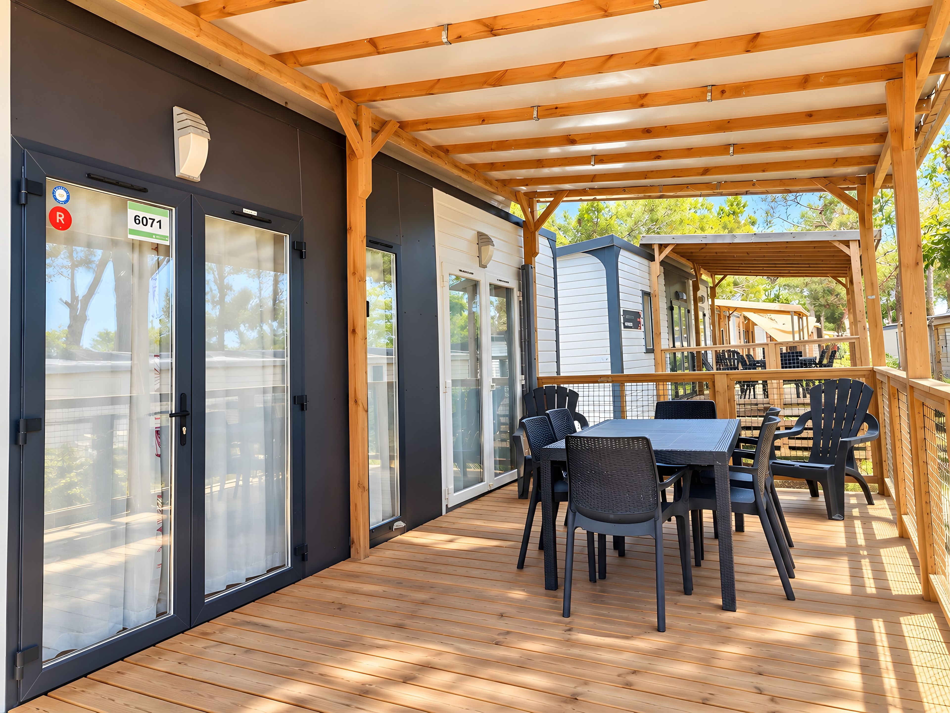 An outdoor patio with a wooden deck, a covered seating area, and a view of the surrounding landscape.