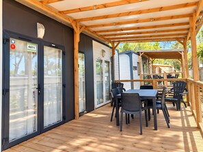An outdoor patio with a wooden deck, a covered seating area, and a view of the surrounding landscape.