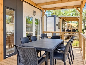 An outdoor patio with a table and chairs, a covered area, and a view of the surrounding neighborhood. - Caravan '5-star Family' with Shared Pool, Private Terrace and Air Conditioning (Vendres)
