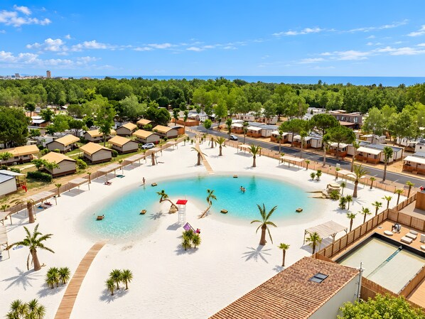 A resort with a central swimming pool, beach area, and multiple bungalow-style accommodations.