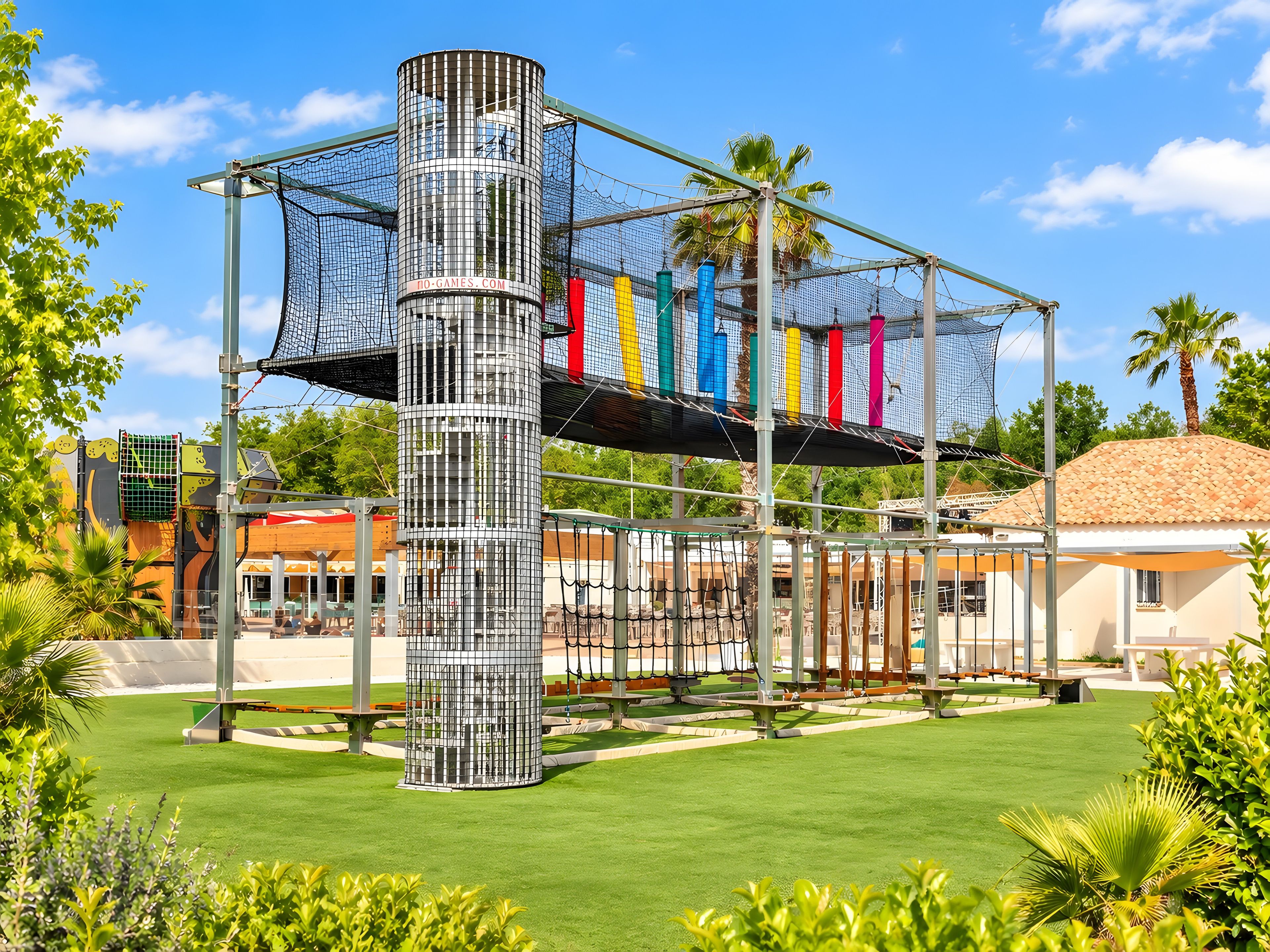 A playground with a climbing structure, a palm tree, and a building in the background.