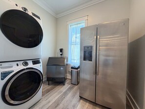 Een compacte keuken met een koelkast van roestvrij staal, een wasmachine en een koffiezetapparaat.