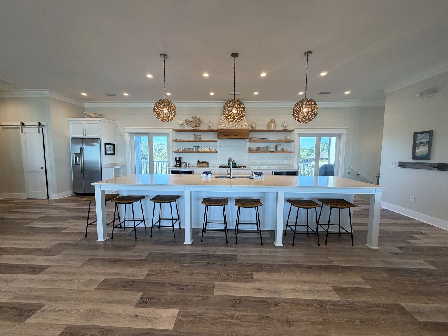 A spacious kitchen with a central island, pendant lighting, and a refrigerator.