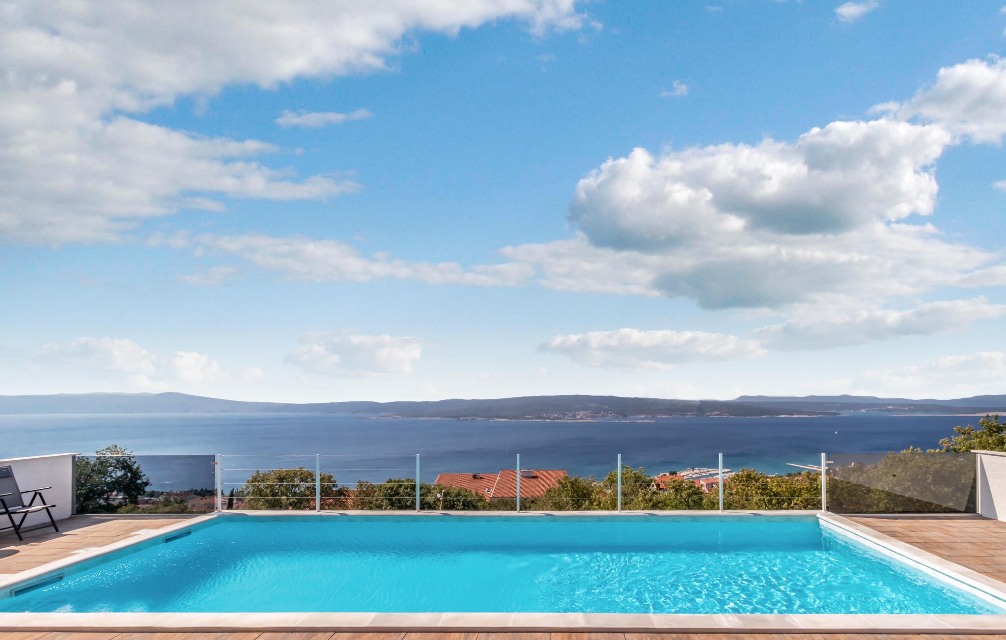 A rectangular swimming pool with clear blue water, surrounded by a wooden deck.