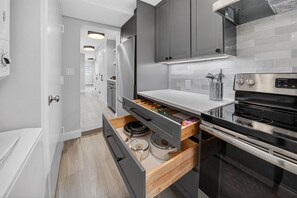 A modern kitchen with grey cabinets, a stainless steel refrigerator, a built-in oven, and a countertop with a coffee machine. - Renovated Capitol Hill 1BR – 2 Blocks to Metro, Parking (Washington)